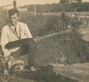 Photo of Leslie Woolston – Old photo of Leslie Woolston beside a boat holding an oar