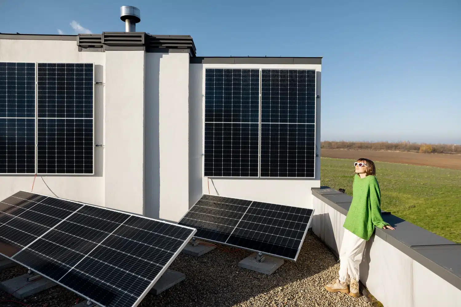 woman-on-the-roof-of-her-house-with-a-solar-statio-2025-03-16-06-58-27-utc Homeowner enjoying the benefits of sustainable energy from solar panels installed by Smartway Builders.